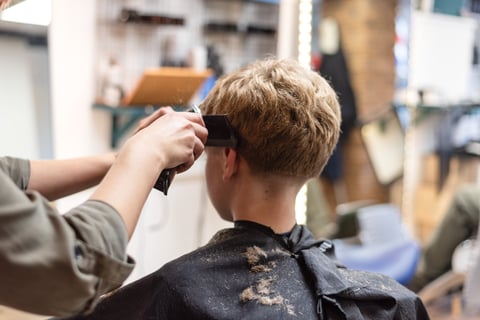 Hairstylist cutting a young boys hair in a salon