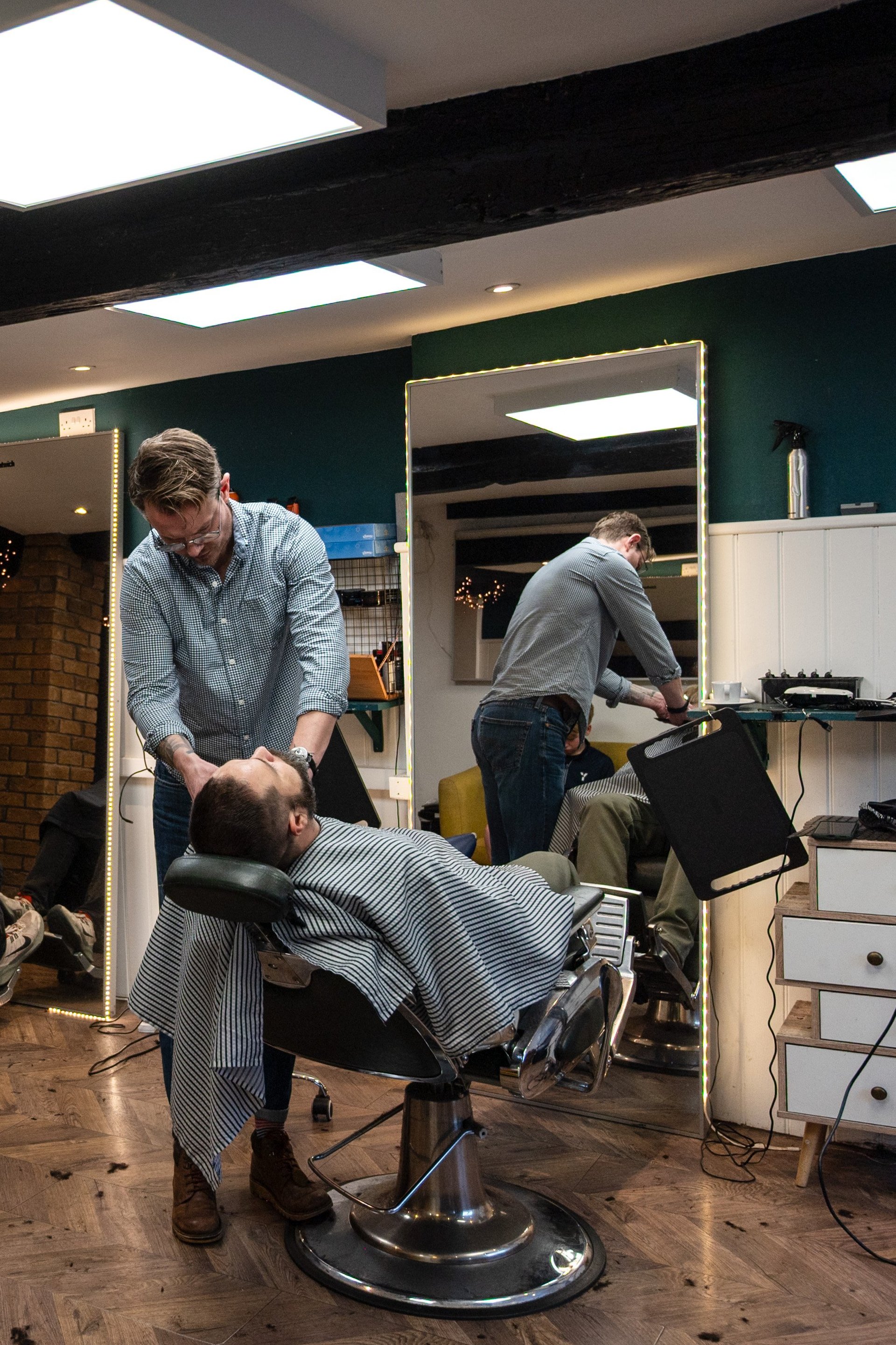 Tonsorium barbershop interior with teal walls and modern styling stations