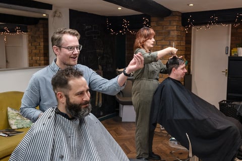 Barber cutting customers hair in a salon with festive decorations